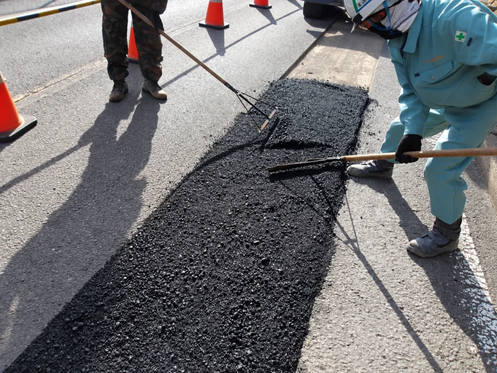 小榊線線路変更工事（管路工事）：管路施工箇所にアスファルト合材を敷きならす仮舗装作業