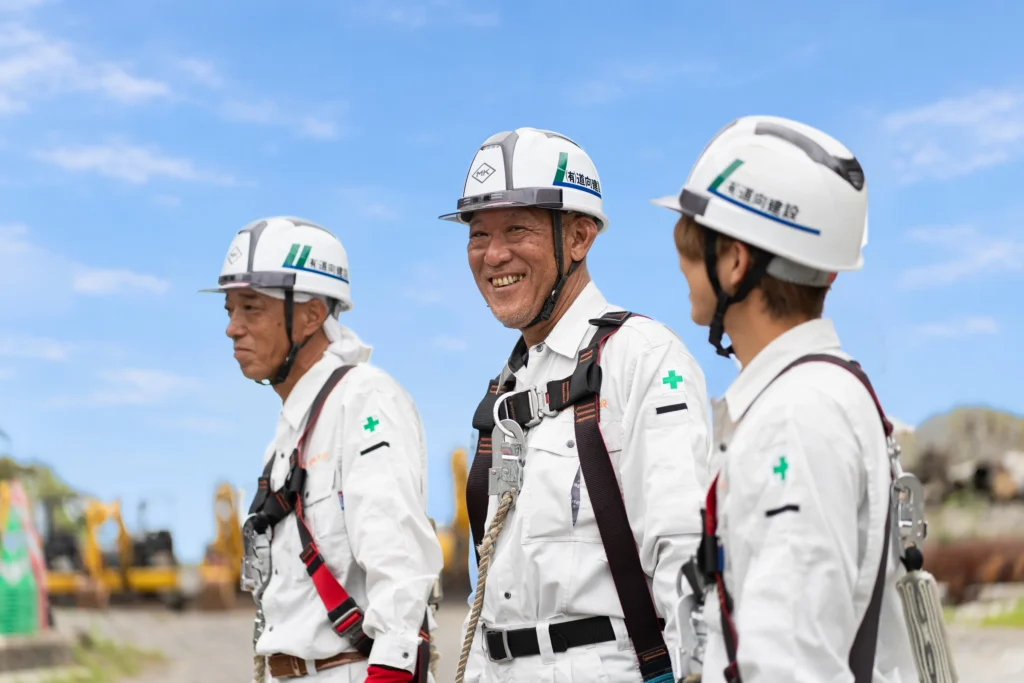 笑顔を交わすヘルメット姿の社員3人