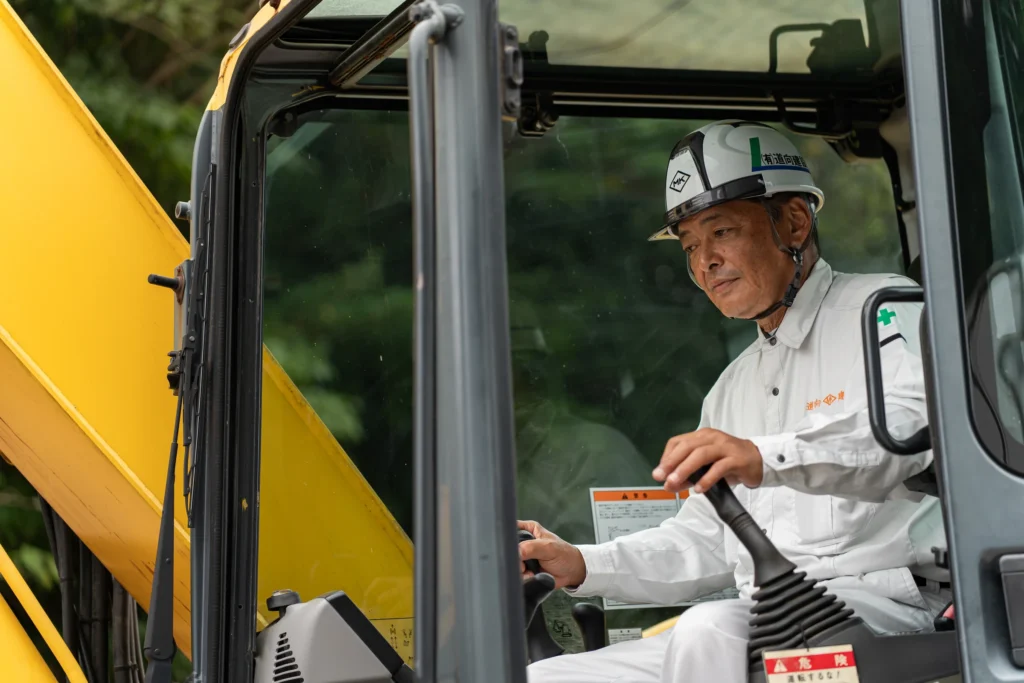 ヘルメットを着用し重機の運転席に座る社員