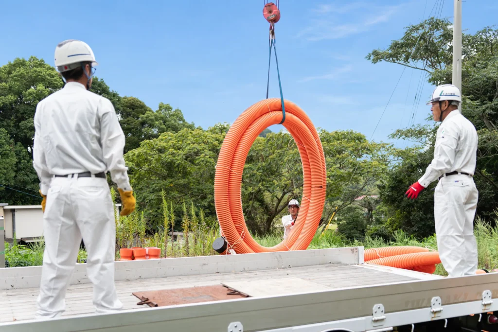 管材をクレーンで搬入する道向建設の作業員