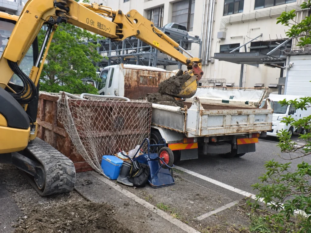 長崎スタジアムシティ供給工事(MH据付):バックホウで残土をダンプへ積み込む作業