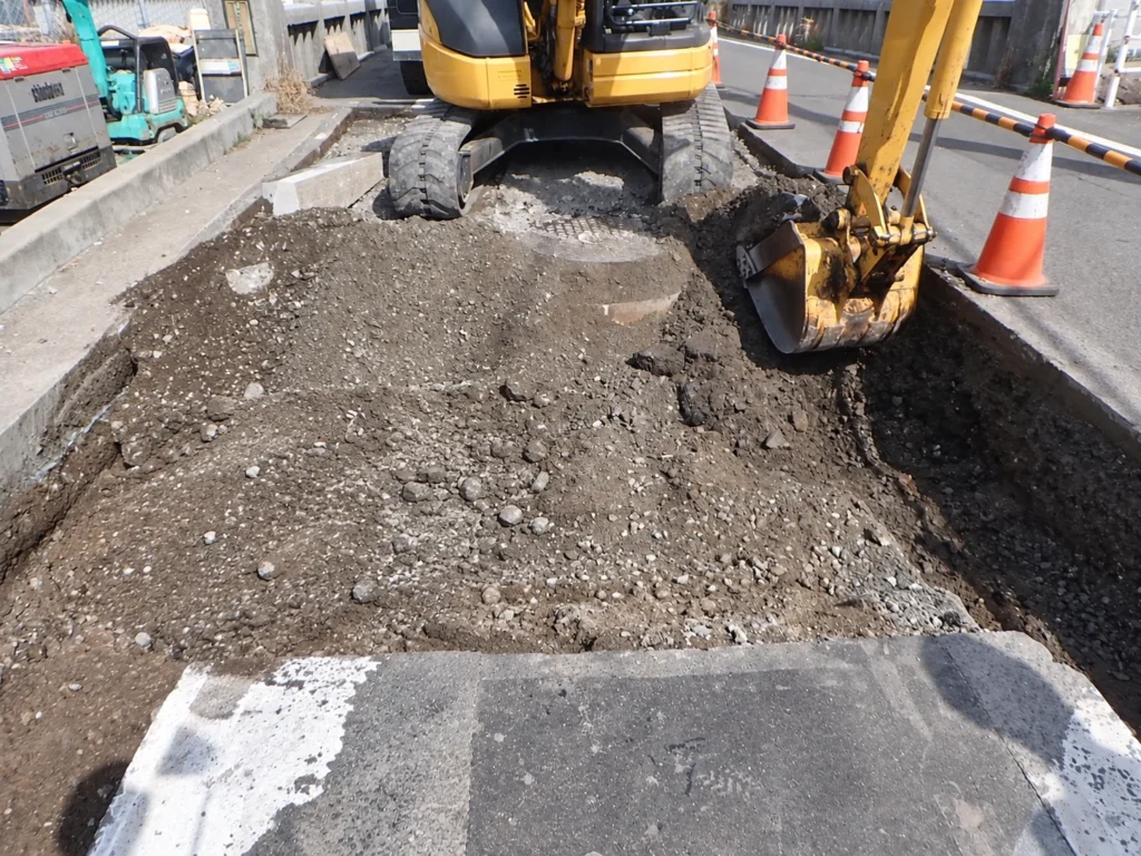 長崎駅周辺土地区画整理事業（2工区）電線共同溝工事：既設地中設備の撤去に伴い、道路を掘削する作業